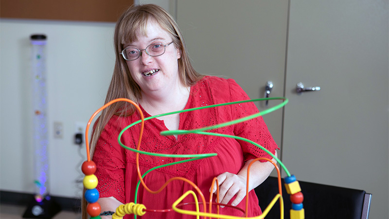 Indoor photo of a female playing with a beads maze toy