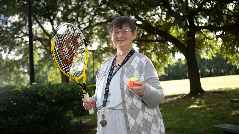 Outdoor photo of a senior woman with a tennis racket